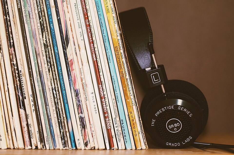 Open-back Grado headphones beside a shelf of records