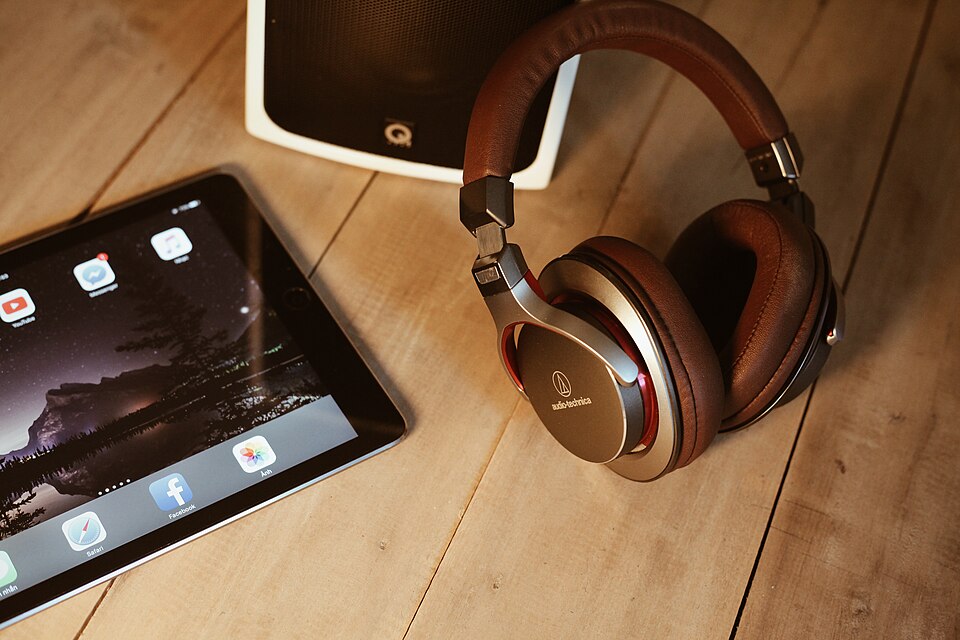 Brown headphones on a desk next to a tablet